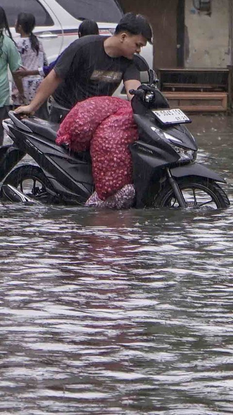 FOTO: Drainase Meluap, Warga Pasar Rebo Terobos Genangan