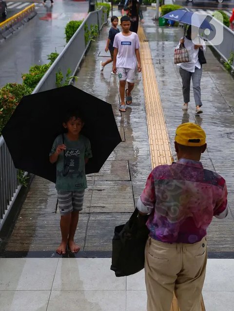 FOTO: Potret Anak-Anak Pengojek Payung di Antara Gedung Bertingkat Jakarta