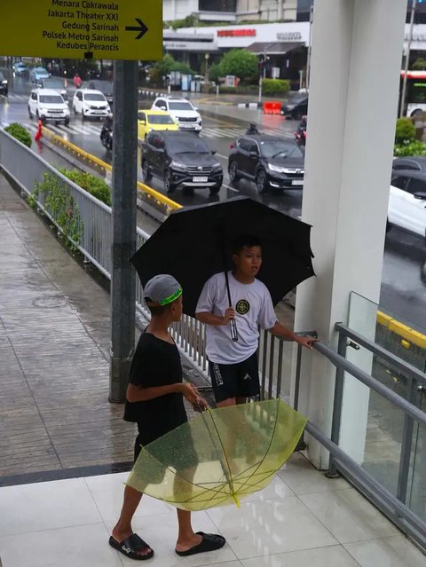 FOTO: Potret Anak-Anak Pengojek Payung di Antara Gedung Bertingkat Jakarta