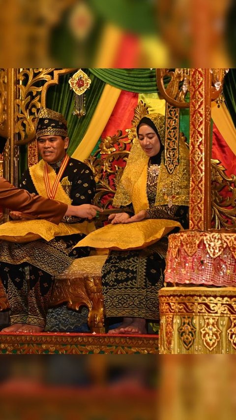 Sang istri pun tampak anggun mempesona memakai busana yang didominasi warna hitam dan emas tersebut.<br>