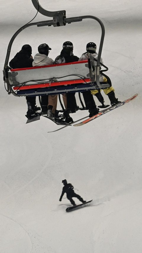 Sejumlah pengunjung menggunakan kereta gantung menuju puncak seluncur es pada Shanghai L+SNOW Indoor Skiing Theme Resort. Foto: Hector Retamal/AFP