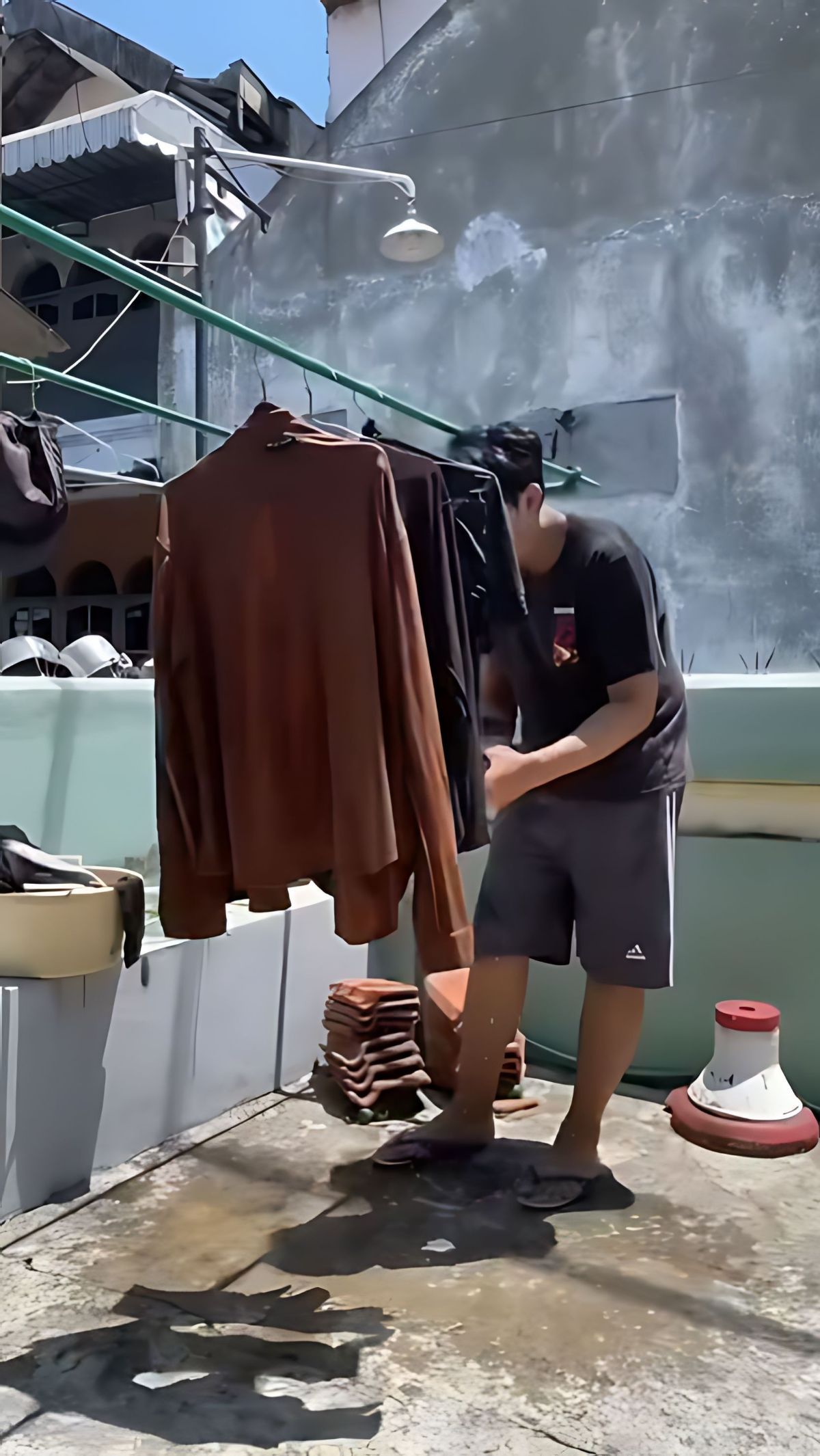 Tak lama terlihat Rizky sudah sibuk menjemur beberapa bajunya di teras rumahnya.