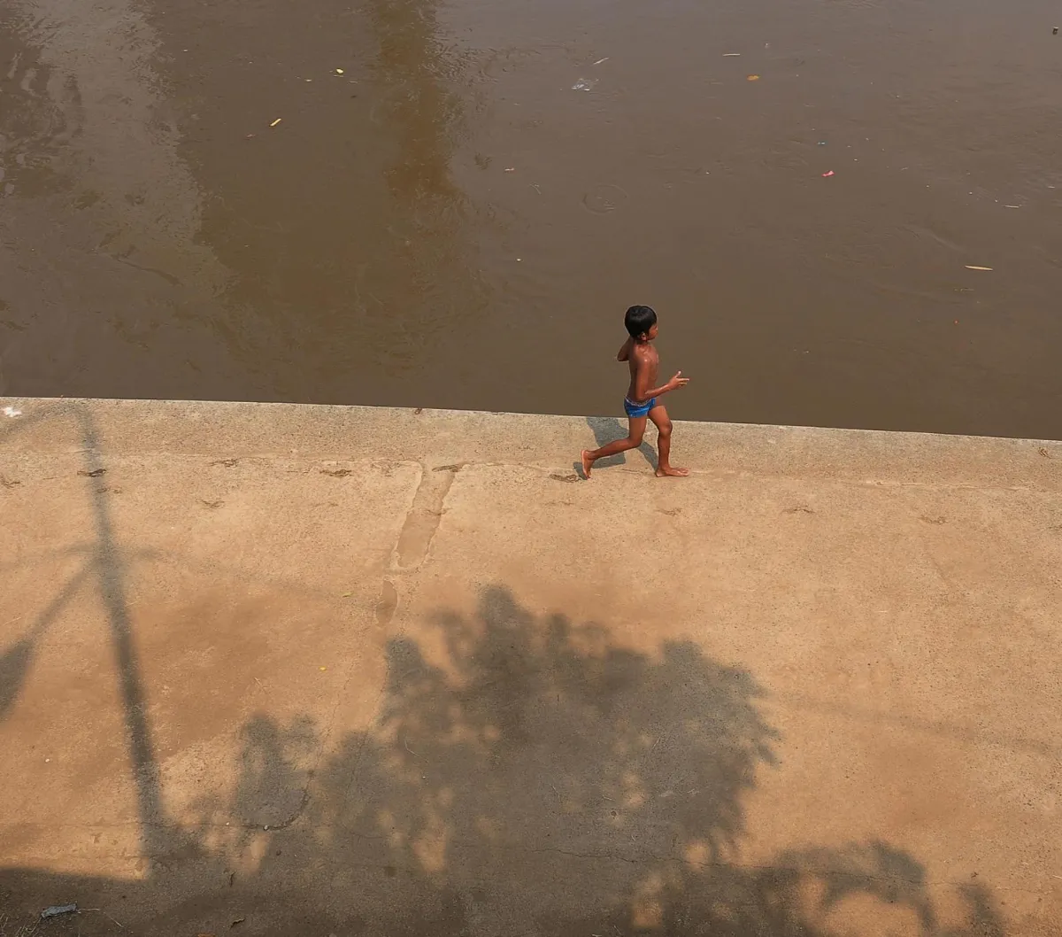 Seorang anak saat sedang asyik bermain di pinggiran kali Ciliwung di kawasan Cawang, Jakarta, Kamis (16/11/2023). Awal musim hujan di Indonesia diperkirakan mulai pada Oktober hingga Desember 2023.