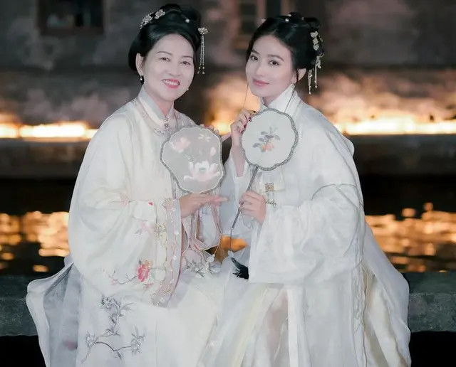 Tidak hanya Natasha, sang ibu juga mengenakan pakaian tradisional serupa dan kompak membawa kipas khas China, menciptakan kesan yang serasi di antara keduanya.