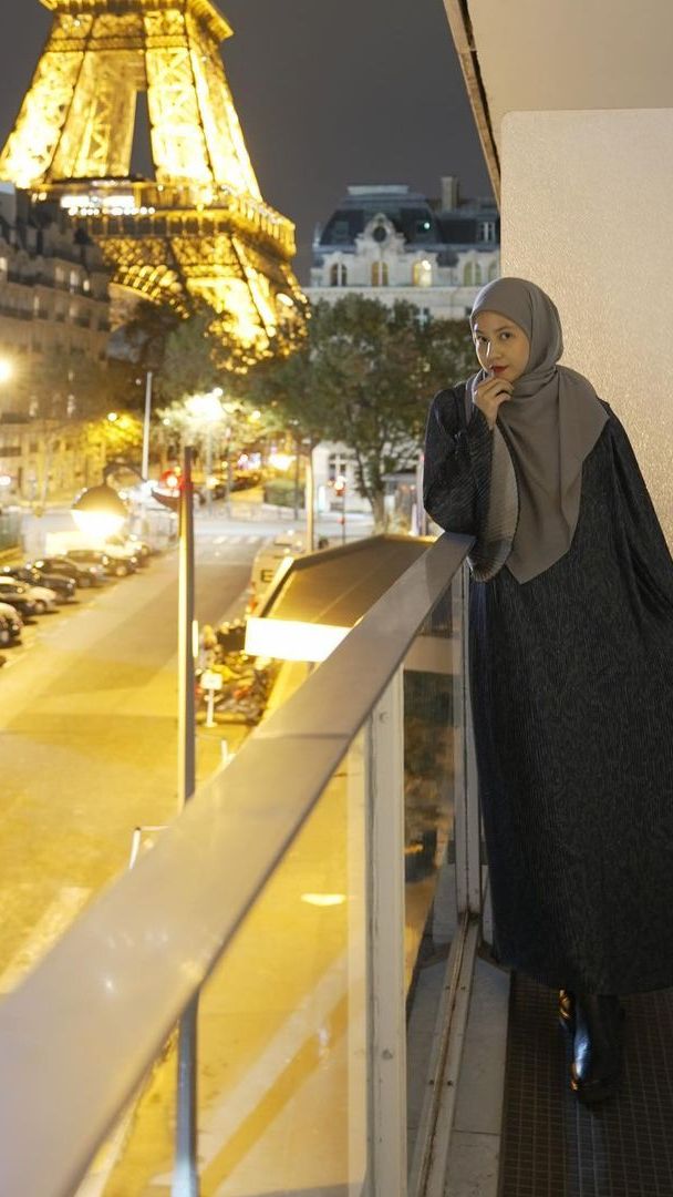 Natasha membagikan potret dengan latarMenara Eiffel. Dia terlihat mengenakan dress hitam corak hijau tua, dipadukan hijab berwarna abu-abu.