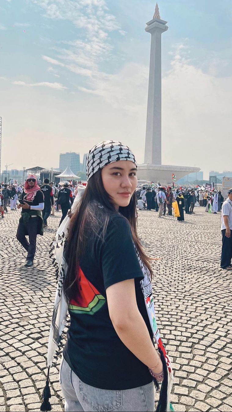 Aaliyah Massaid yang pose depan Monas tampak cantik dengan kaos hitam bergambar semangka dan sorban di kepala khas Palestina.