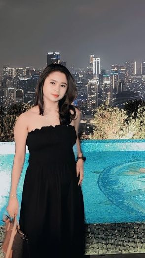 Penampilannya pun serasa sosialita dengan dress berwarna hitam dan berpose di samping kolam renang.