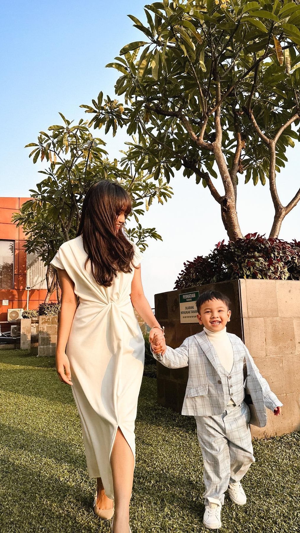 Fuji menggunakan midi dress putih dengan belahan di tengah.