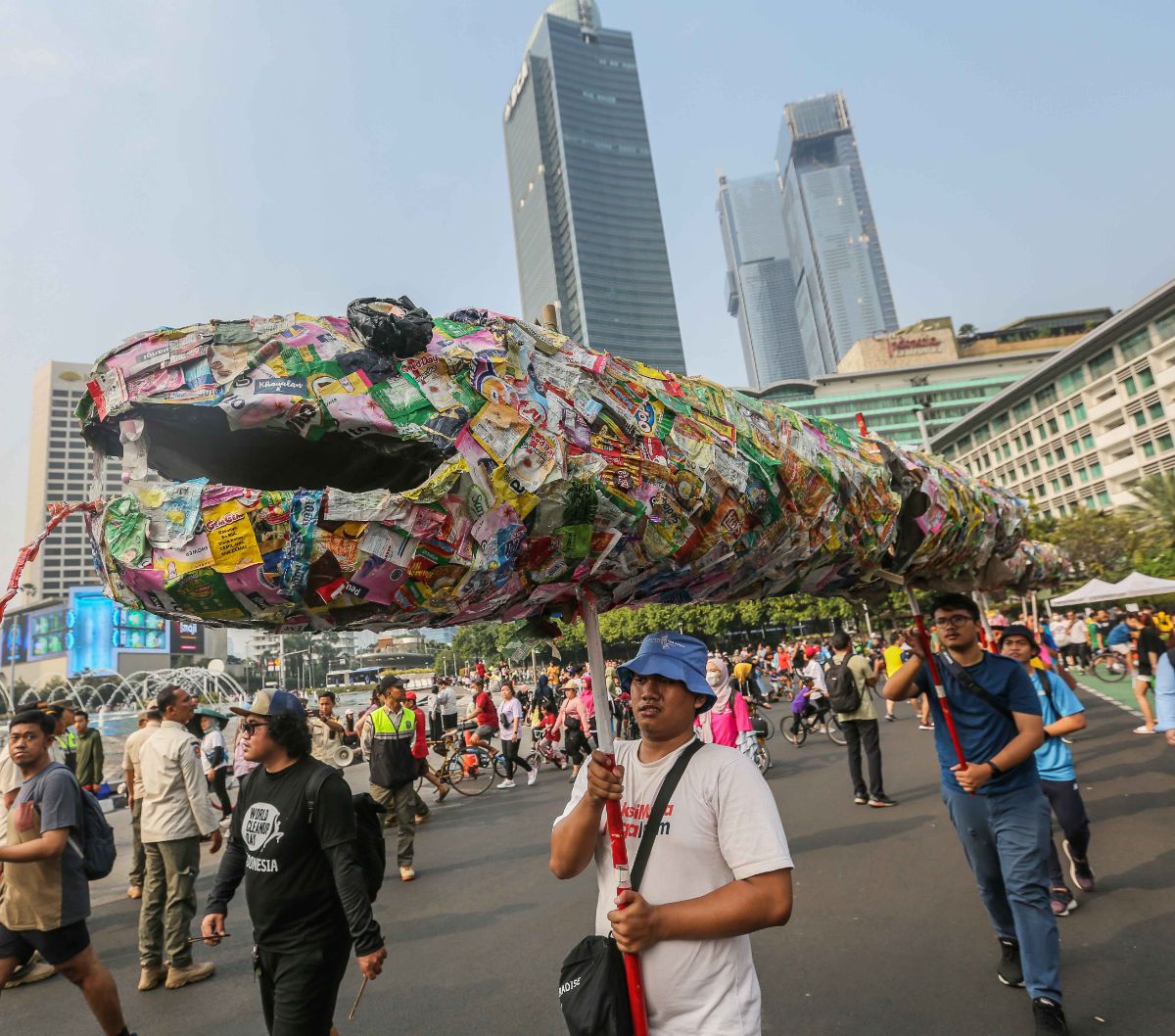 Pegiat lingkungan membawa poster hingga instalasi ular dari sampah plastik saset saat menggelar pawai bebas plastik di Kawasan Sudirman, Jakarta, Minggu (30/7/2023).