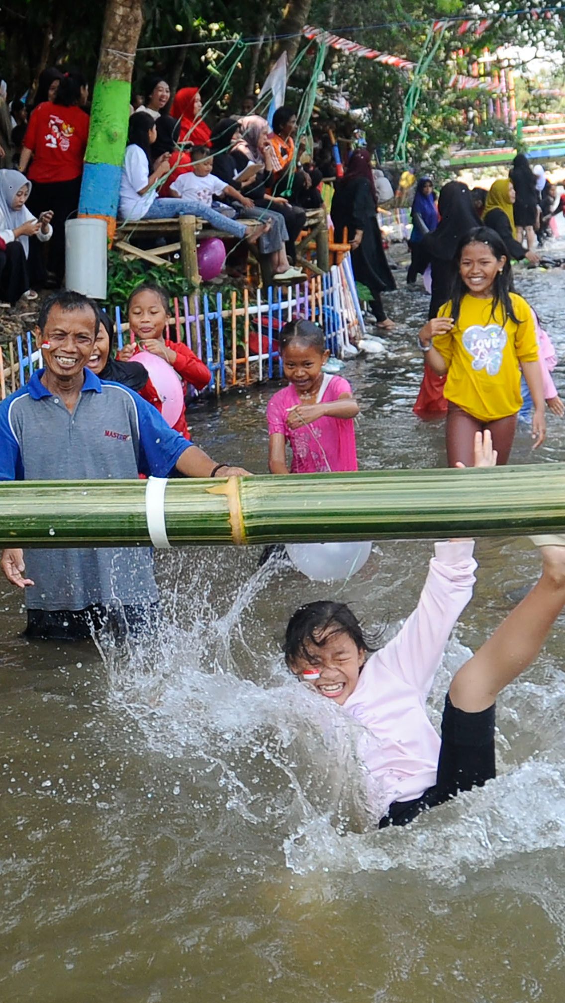 Lomba ini menggunakan batang pohon bambu yang membentang di atas kolam.