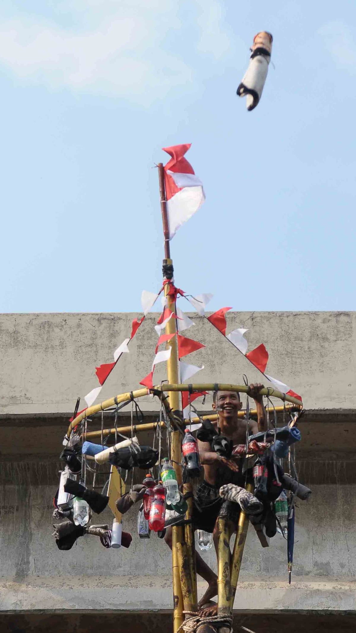 Senyum semringah seorang peserta yang berhasil mencapai puncak pohon pinang.