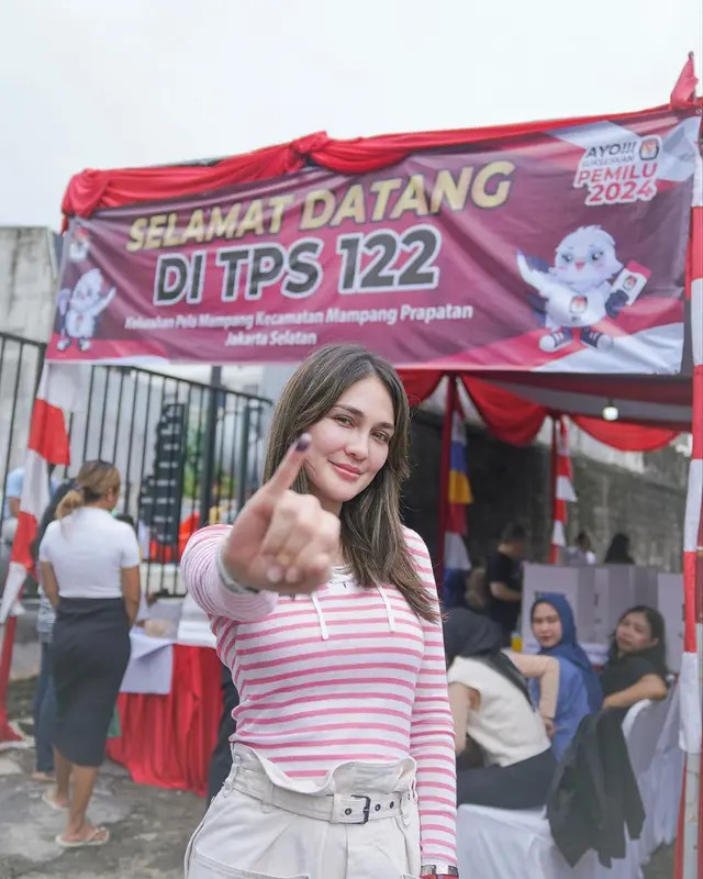 Luna Maya tampil dengan kaos panjang nuansa pink-putih dan celana warna putih gading