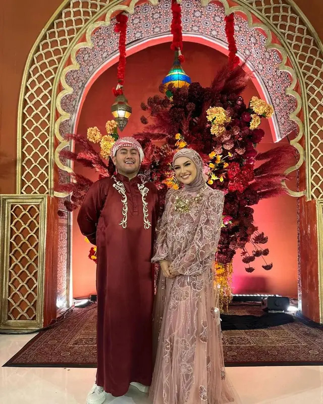 King Nassar bergaya ala raja minyak Arab dengan gamis merah dan sorban.