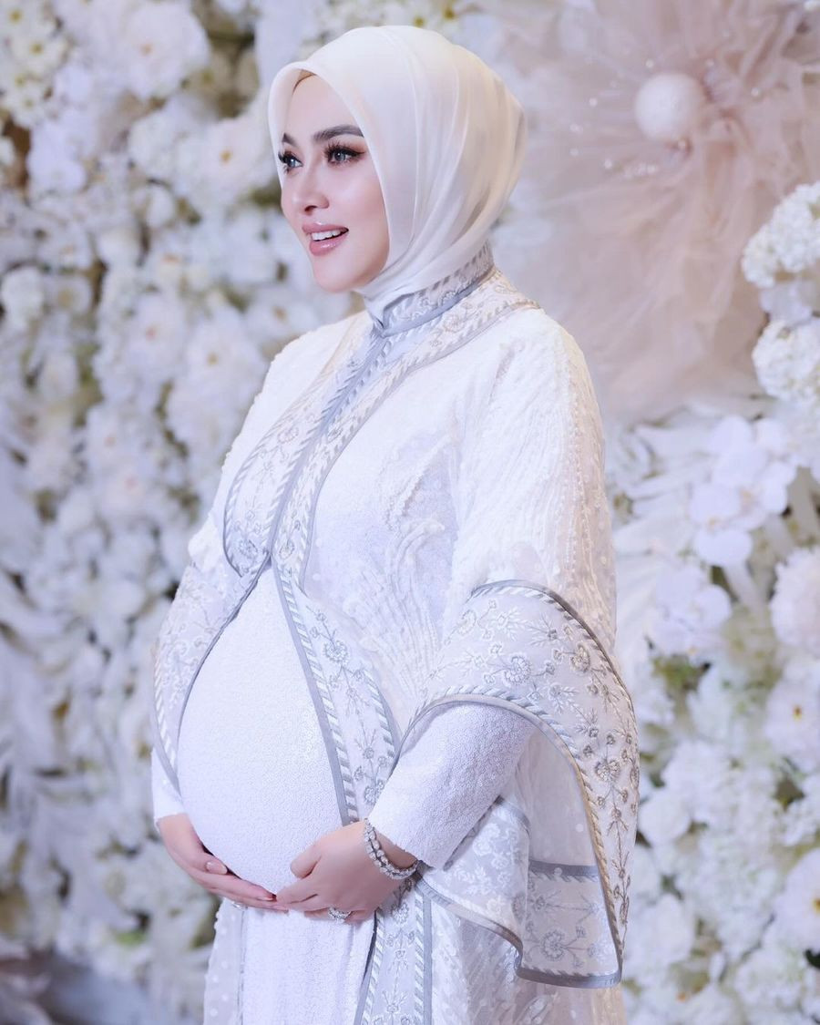 Syahrini tampil dengan busana serba putih sembari memamerkan perutnya.