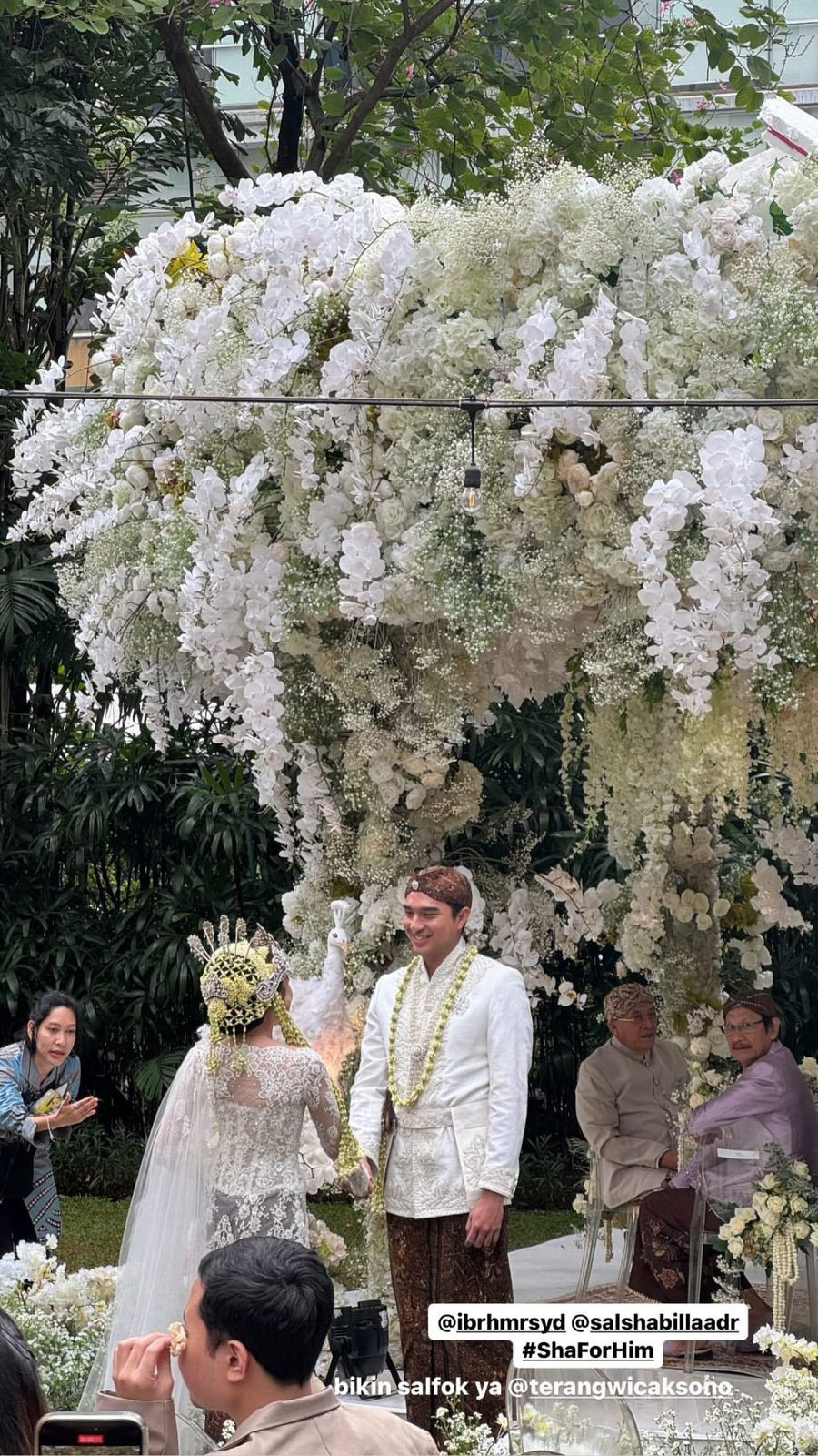 Tak hanya pengantin, dekorasi pernikahan pun begitu mewah dengan hiasan bunga putih yang super banyak.