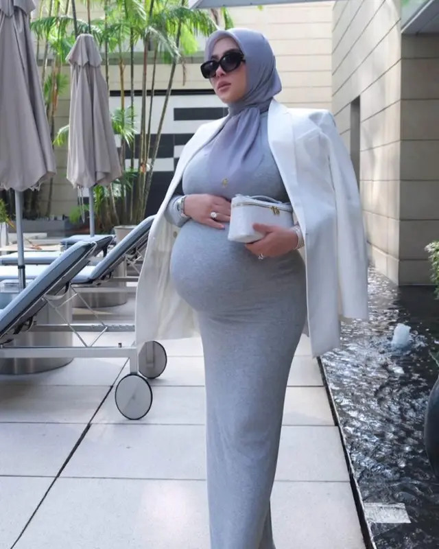 Ia memadukan blazer putih sebagai outer. Tak ketinggalan tas branded yang selalu ditentengnya.