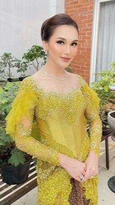 Ayu terlihat anggun dengan kebaya berwarna kuning.