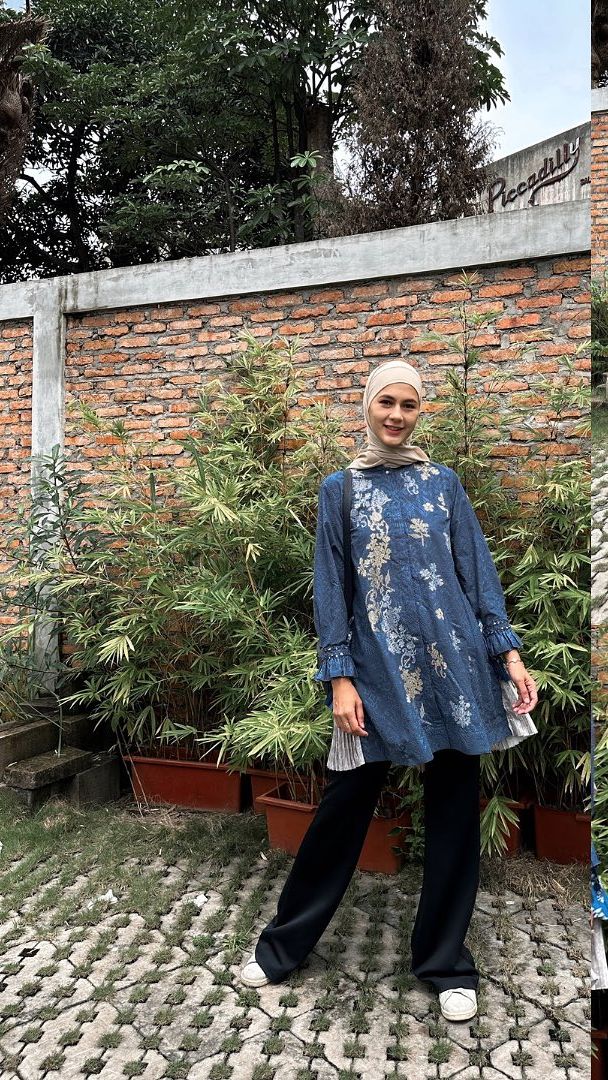 Ibu dua anak ini tampil mengenakan kemeja hijau lengkap dengan hijab berwarna senada
