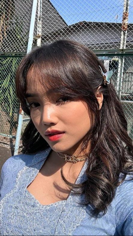 Ia tampil cantik dengan kebaya biru dan menggerai rambutnya.