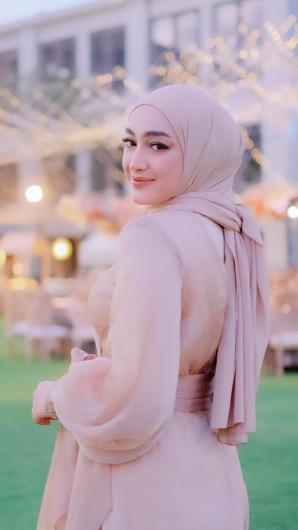 Ia tampil berbeda dengan seragam anggota keluarga lain. Santyka memakai dress satin warna cokelat susu