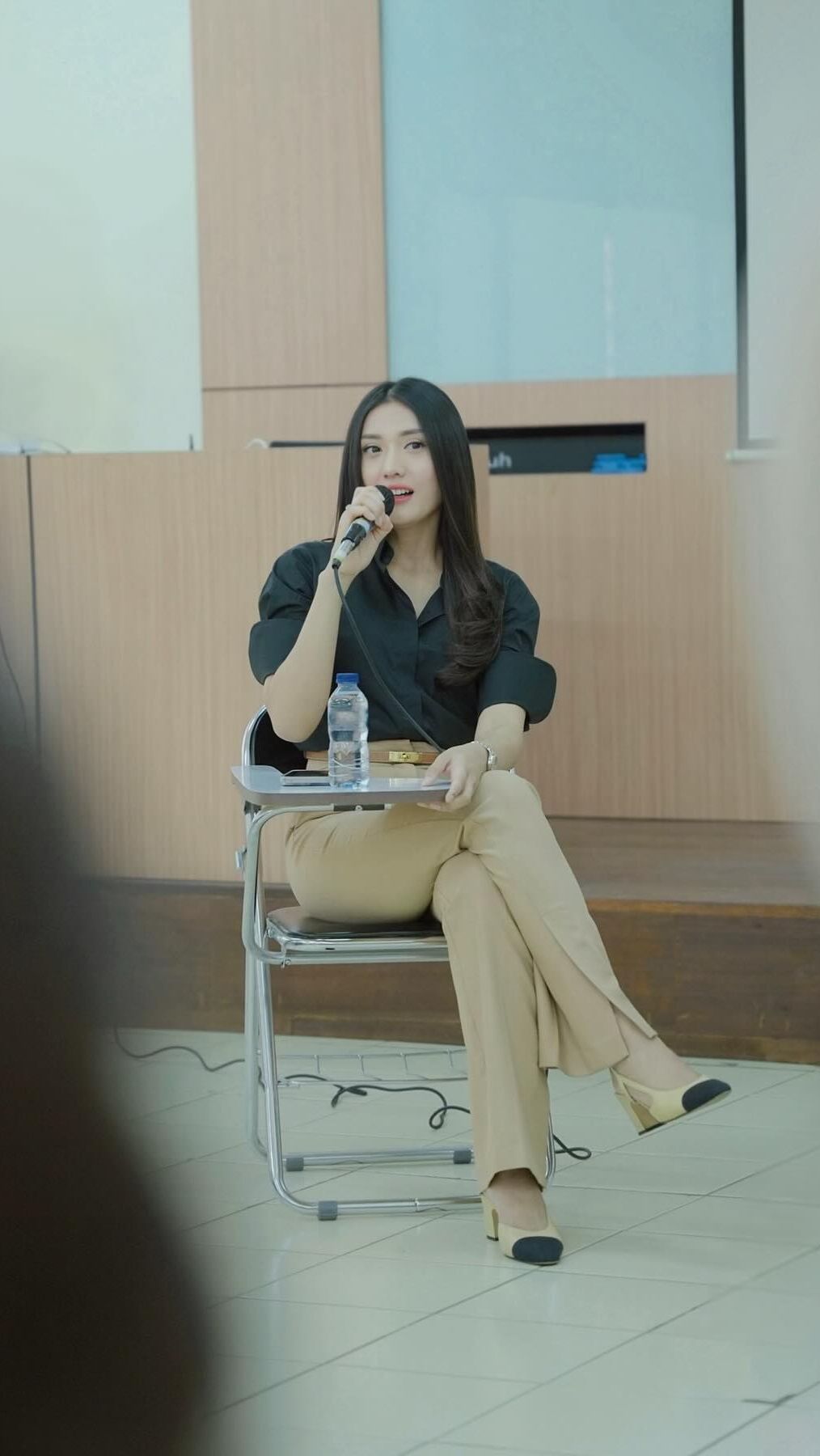 Ia tampil stunning dan elegan dengan kemeja hitam serta celana panjang krem
