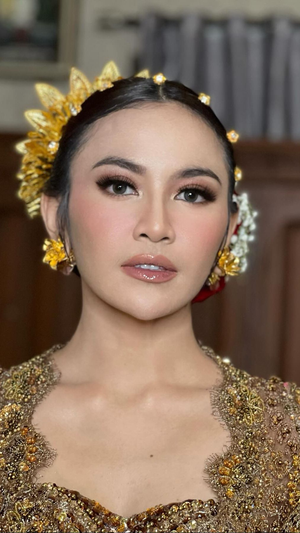 Terlihat area mata diberikan gradasi copper dengan blush on warna peach. Sementara bagian bibir, dipilih lipstik berwarna nude peach dengan efek glossy