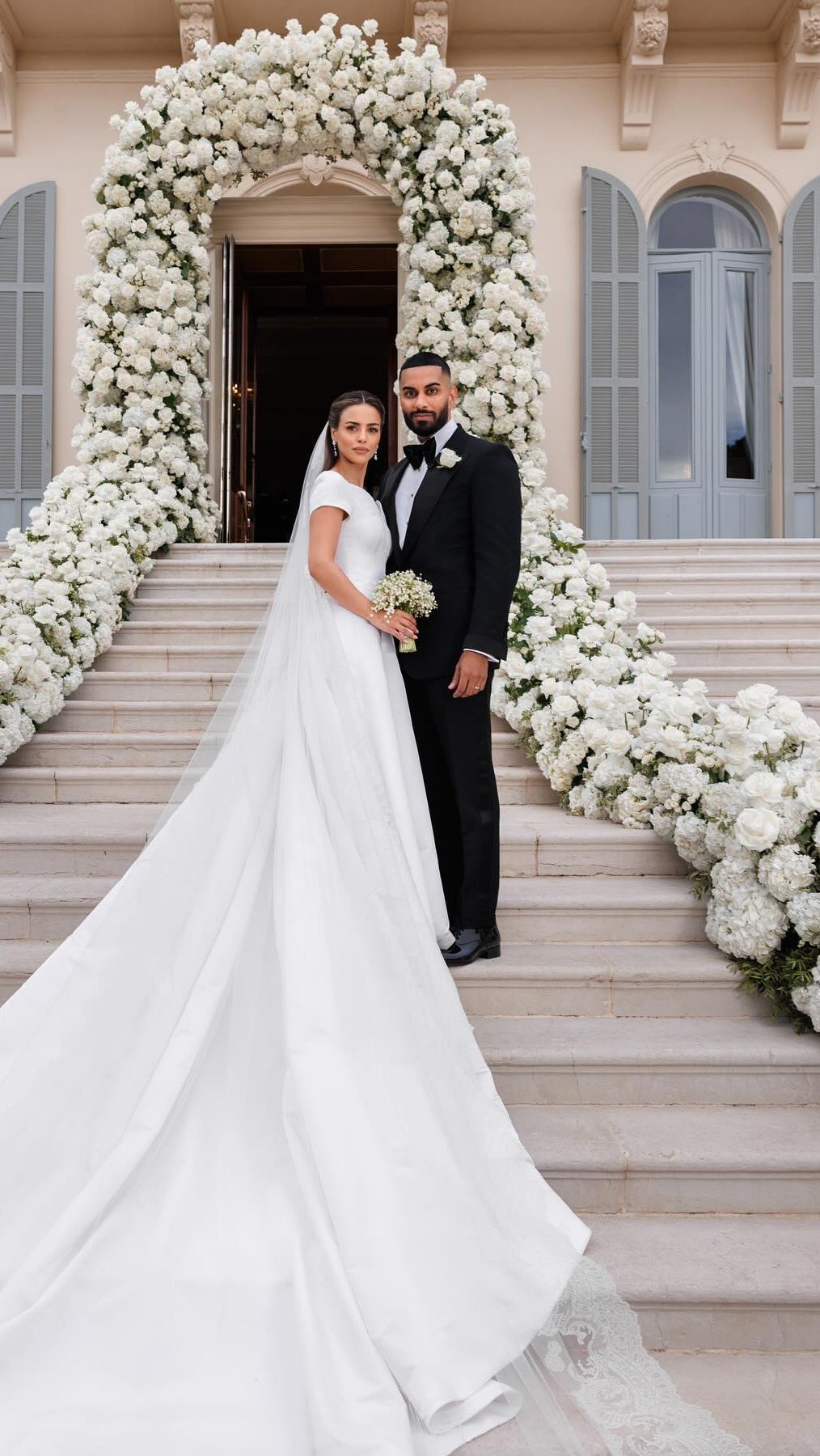 Nada tampil cantik dalam balutan gaun putih dari koleksi Dior yang dirancang oleh Maria Grazia Chiuri. Sementara Umar terlihat begitu tampan dengan setelan jas hitam Tom Ford