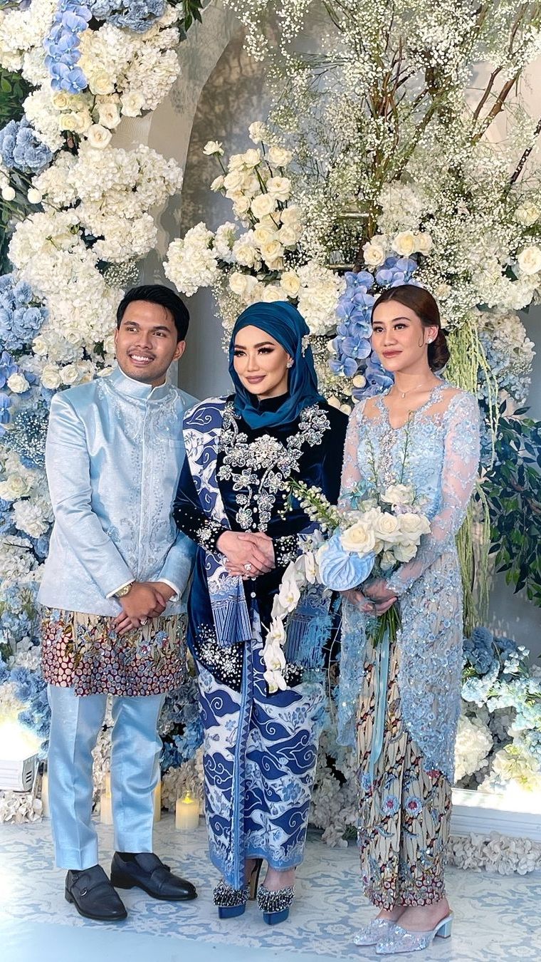 Reza terlihat anggun mengenakan kebaya berwarna biru. Penampilannya berbalut berhijab pun berhasil curi perhatian.