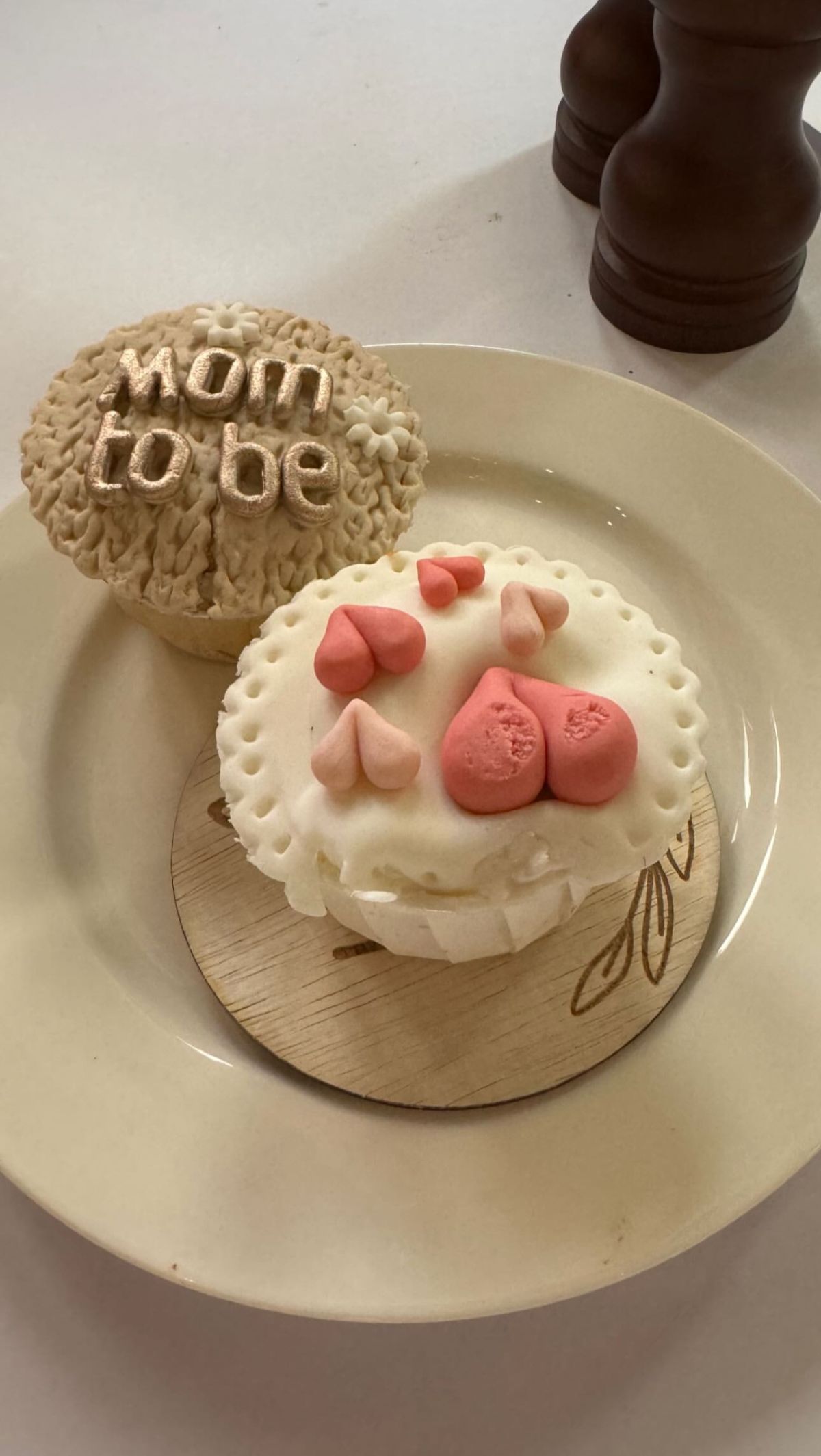 Ada cup cake dengan gambar hati berwarna pink dan tulisan mom to be.