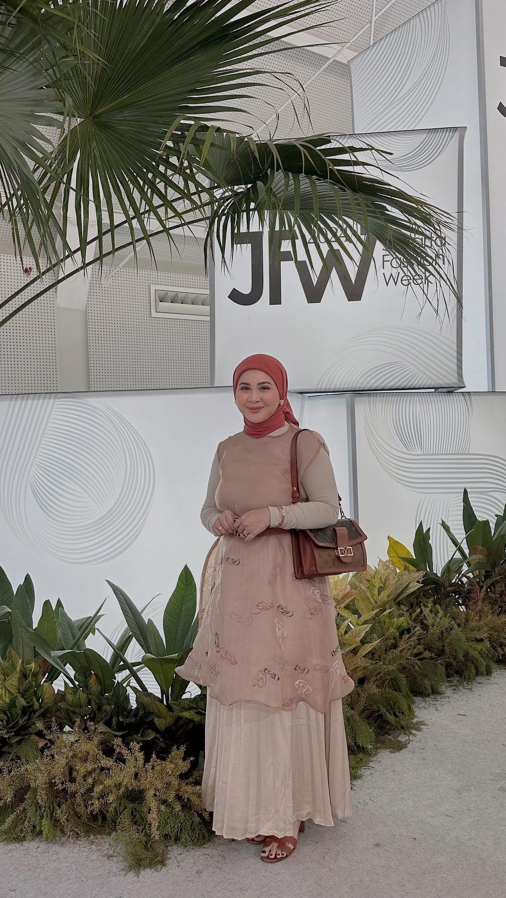 Rok plisket cokelat kembali ia padukan dengan atasan senada dan jilbab warna orange
