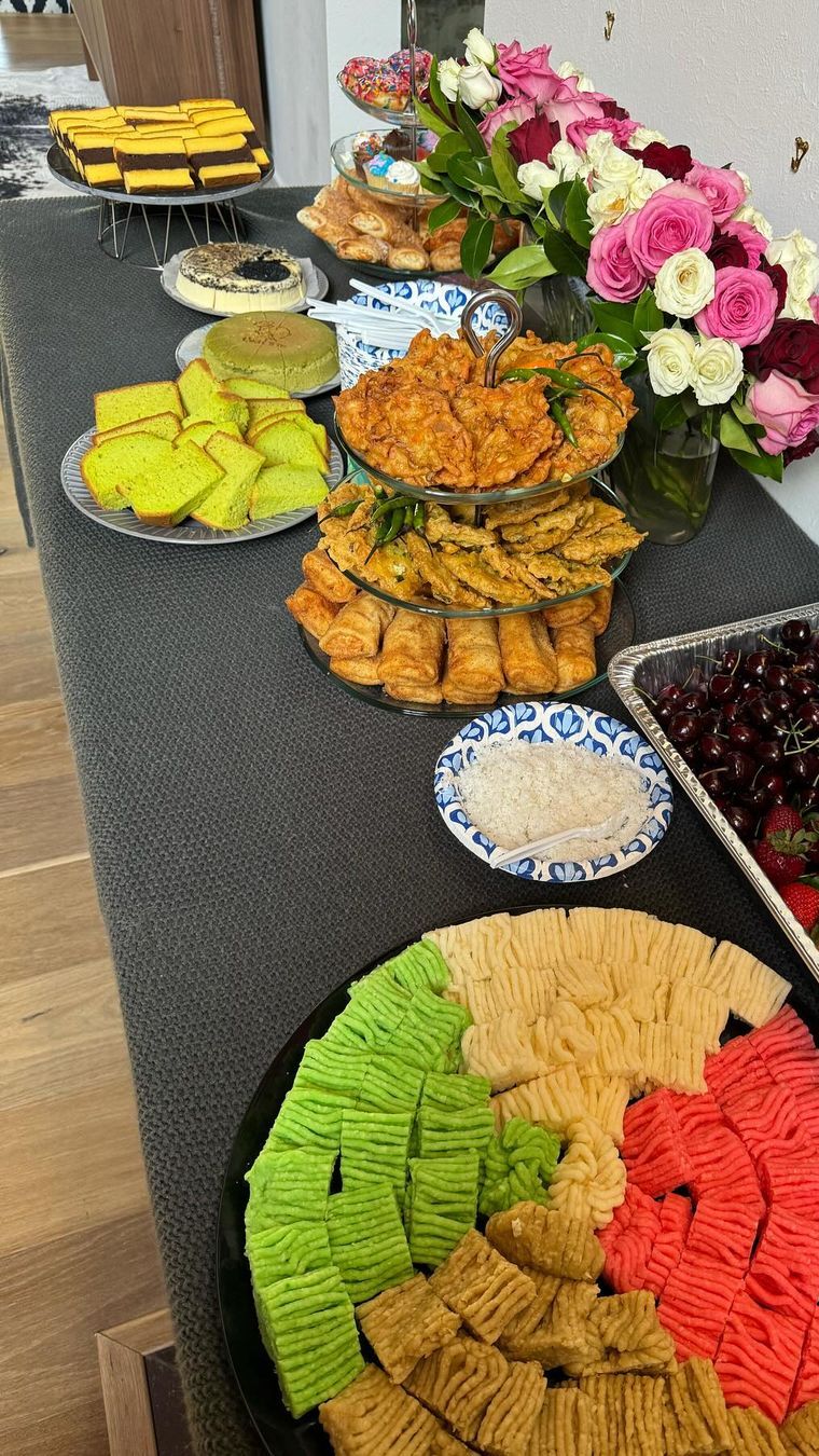 Ada aneka makanan indonesia berada di atas meja dengan hiasan bunga indah.