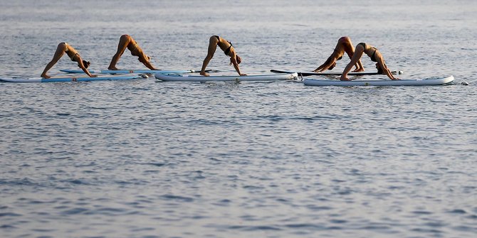 Aksi wanita berbikini latihan yoga di atas Laut Adriatik