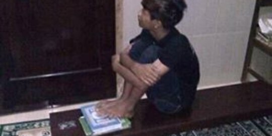 Seorang remaja kedapatan berpose duduk sambil injak Alquran