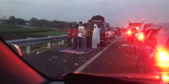 Foto sekeluarga salat di bahu jalan tol banjir pujian
