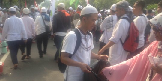Sambil bawa kantong plastik besar, pendemo ini memunguti sampah