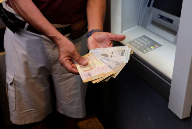 seorang pria menunjukkan uang bolivar setelah menariknya dari mesin atm di caracas