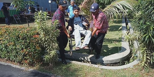 Penyandang disabilitas di TPS 37 Bandung dipapah petugas PPS saat mencoblos