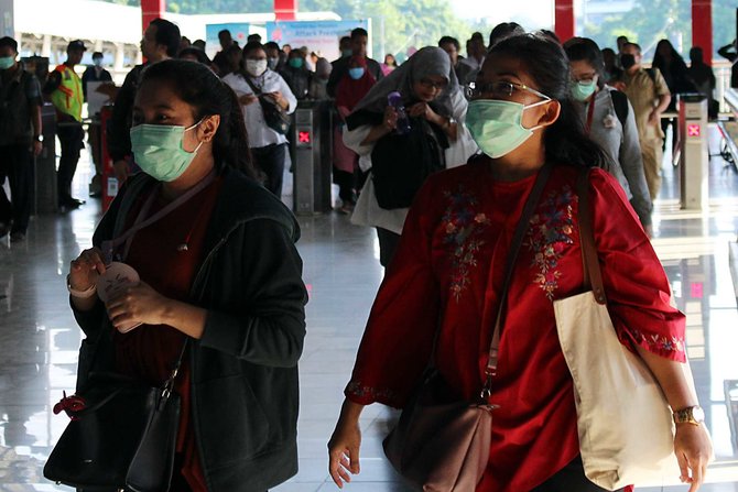 warga memakai masker di stasiun palmerah