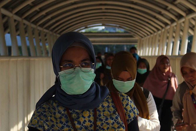 warga memakai masker di stasiun palmerah