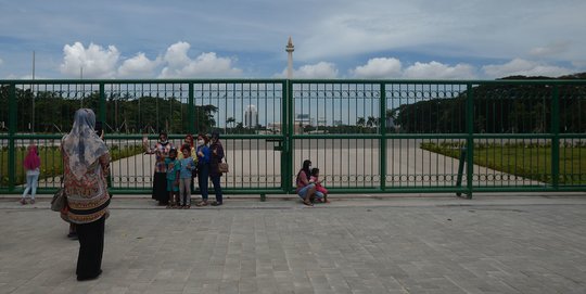 Belum Dibuka, Warga Berfoto di Balik Pagar Monas