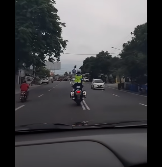 polisi patwal atraksi di atas motor saat mengawal