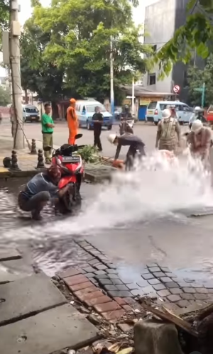 air pdam bocor dan berhamburan ke jalan bapak ini asyik nyuci motor