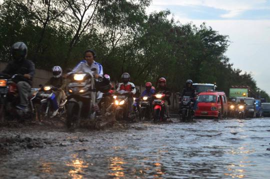 Sejumlah pengendara sepeda motor melewati genangan air di ruas Jalan C 