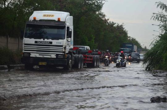 Sejumlah pengendara sepeda motor melewati genangan air di ruas Jalan C 