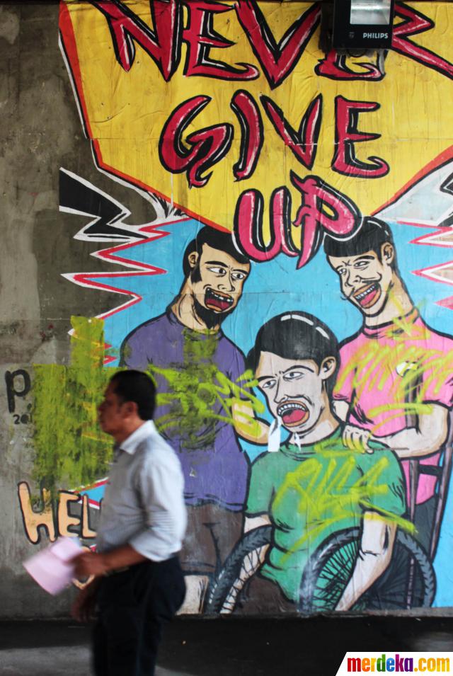 Seorang pejalan kaki melintas di depan mural yang berada di kolong Fly Over di Slipi, Jakarta (8/4). Jelang ulang tahun Kota Jakarta yang ke 486, Pemkot DKI berencana akan mengecat kolong fly over dan tembok under pass agar bersih dari mural dan grafity, untuk kemudian dihias dengan tanaman agar tampak lebih hijau.