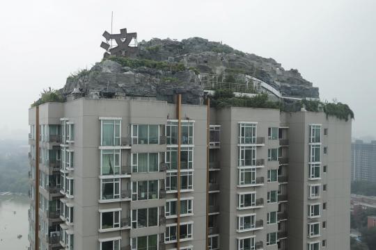 Bongkahan batu raksasa ini tumbuh di atas apartemen