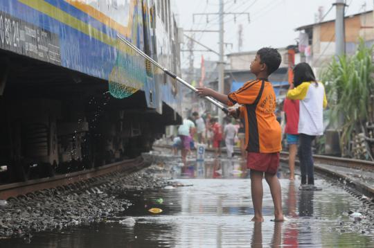 Rel kereta tergenang air, warga Kampung Bandan asyik cari ikan