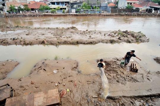 Bersih-bersih lumpur sisa banjir di Kampung Melayu