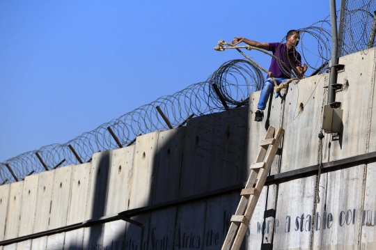 Hindari penjagaan Israel, warga Palestina panjat tembok pembatas