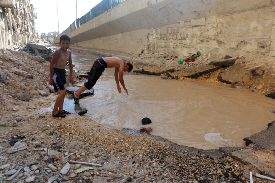Keceriaan bocah Suriah main air di kubangan bekas serangan bom